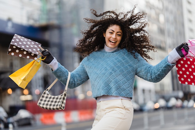 Happy girl wearing blue shirt and white pants in winter after she bought a bunch of things